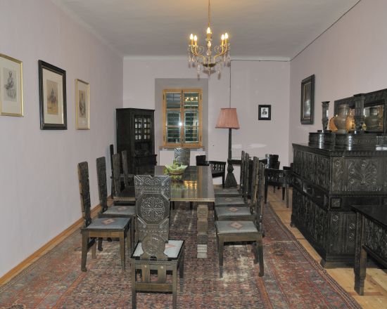 Na zidu so slike s črnim okvirjem. Jedilnica je iz črno lužene hrastovine.
